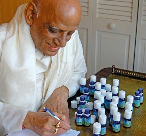 Photo of Vaidya Achyutanand Pati, M.D. Ayu. (G.A.U.) sitting at a desk with many bottles of VedAroma essential oils before him and writing recommendations.