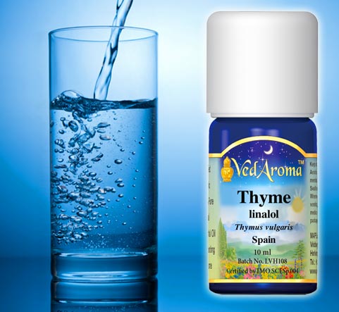 A bottle of VedAroma Thyme linalol essential oil is shown with a photo of water being poured into glass of water