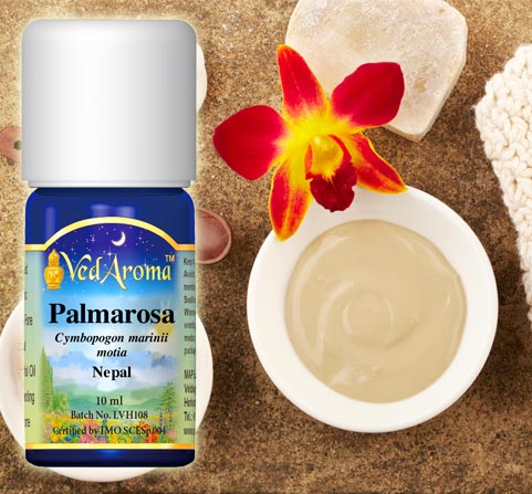 A bottle of VedAroma Palmarosa essential oil is shown with a photo of a a bowl of clay for a facial mask.