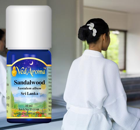 A bottle of VedAroma Sandalwood essential oil is shown with a photo of two women sitting in meditation.